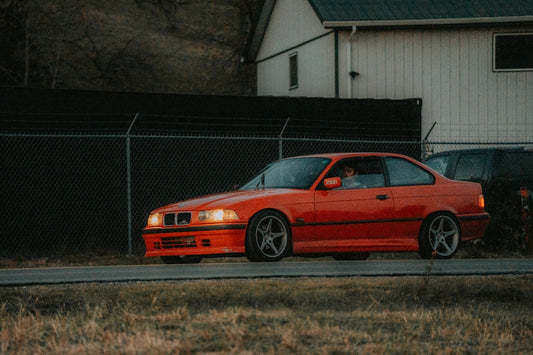 A red car parked next to a black fence